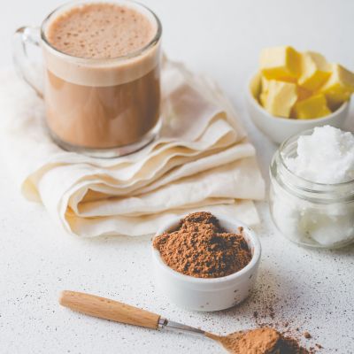 BULLETPROOF CACAO. Ketogenic keto diet hot drink. Cacao blended with coconut oil and butter. Cup of bulletproof cacao and ingredients on white background