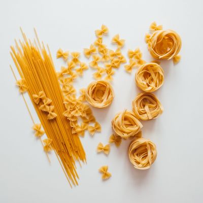 Varieties of Italian pasta. Spaghetti, farfalle and tagliatelle isolated on a white background, top view. Non-perishable food
