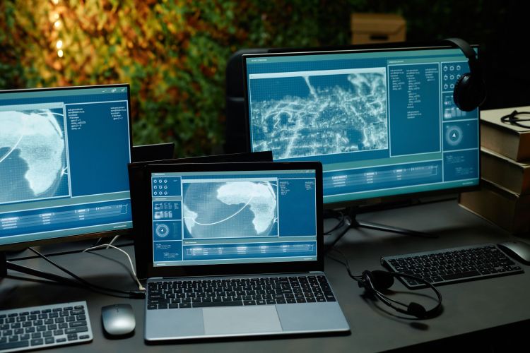 Two computer monitors and laptop with information from cameras on screens